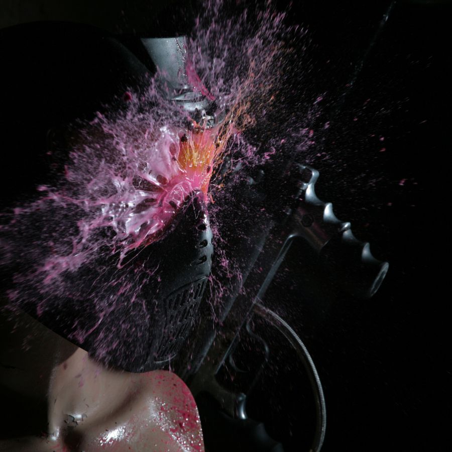 Close up of paintballs hitting mask bursting polyethylene glycol, dye and other components