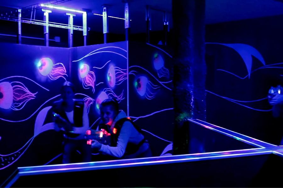 Women playing laser tag in dimly-lit indoor arena